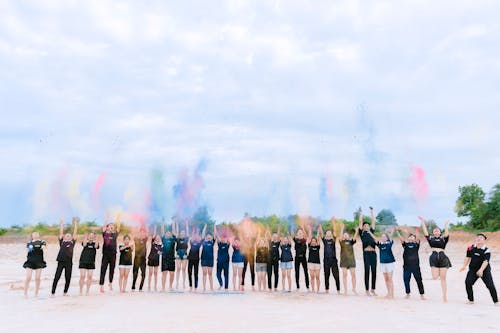 Free Women and Men Throwing Powder on Beach Stock Photo