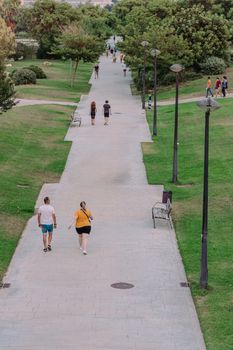 People enjoying a summer walk in a Valencia park with lush greenery.
