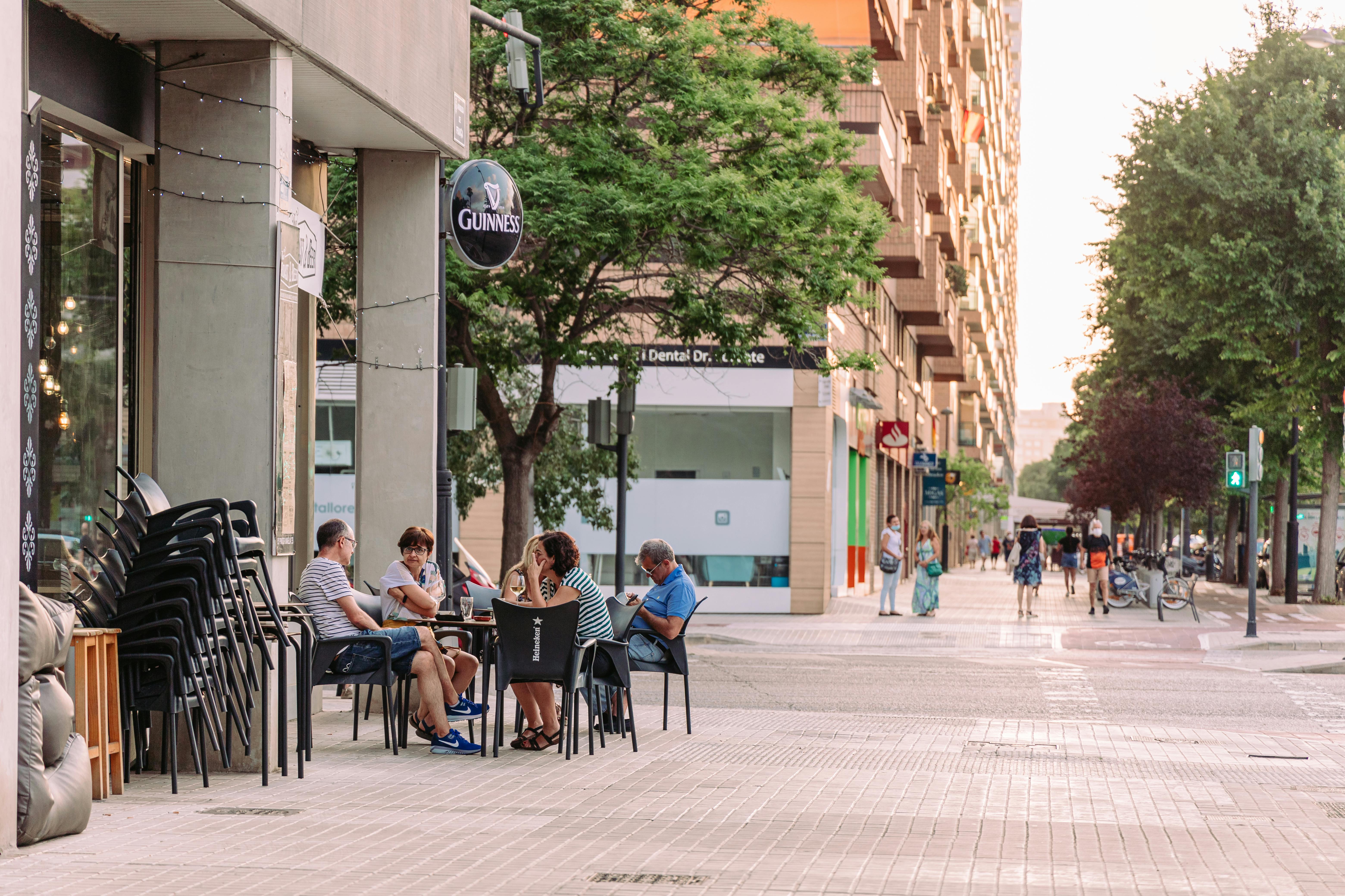 people sitting at tables on a sidewalk in a city
