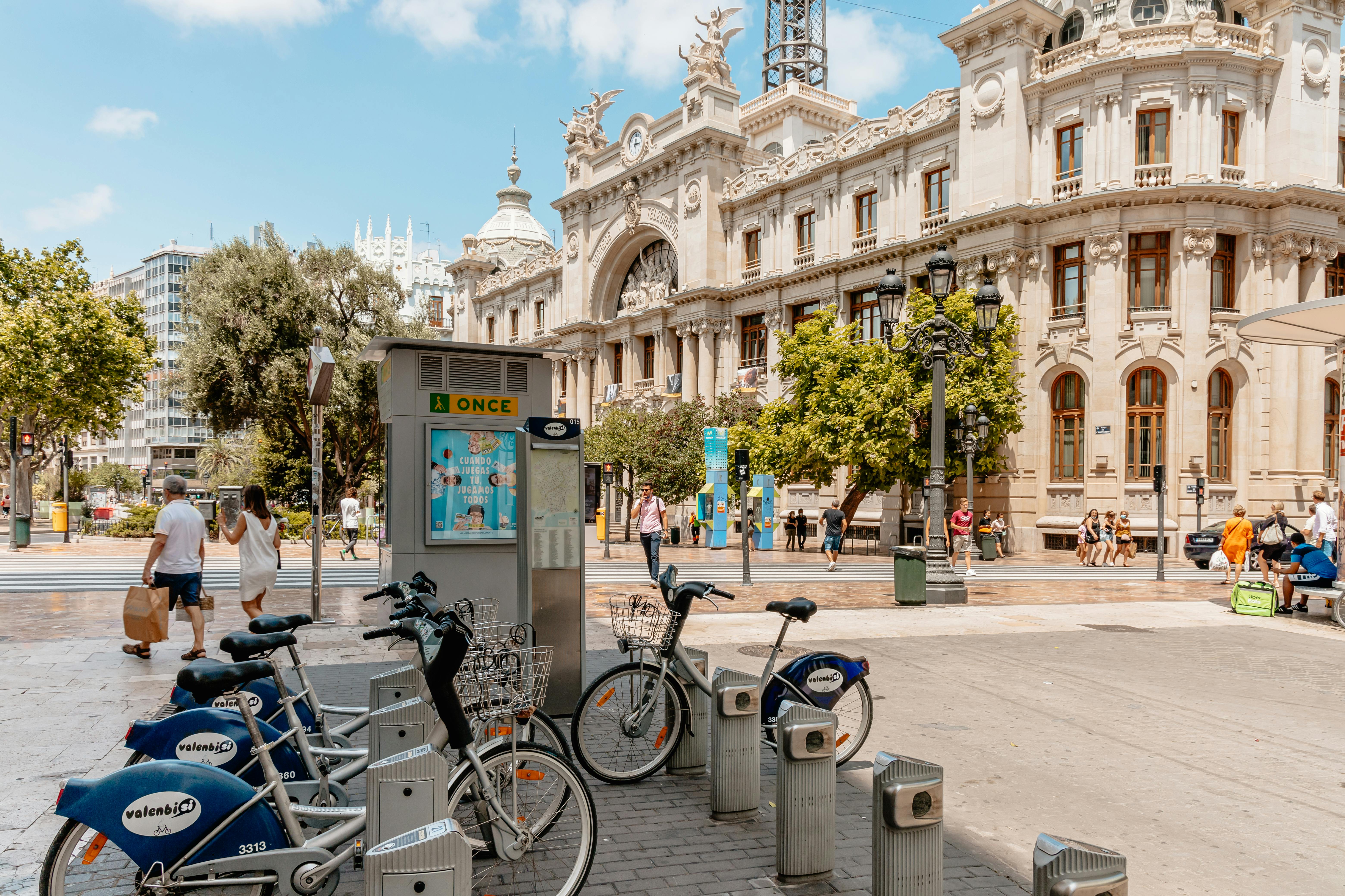 Bikes and people near the historical Plaza del Ayuntamiento in Valencia, perfect for cultural exploration.