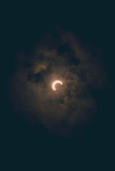 A moody lunar eclipse surrounded by dense clouds in Akumal, Mexico's night sky.