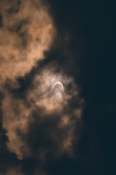 A solar eclipse partially hidden by dramatic clouds, captured in Akumal, Mexico.
