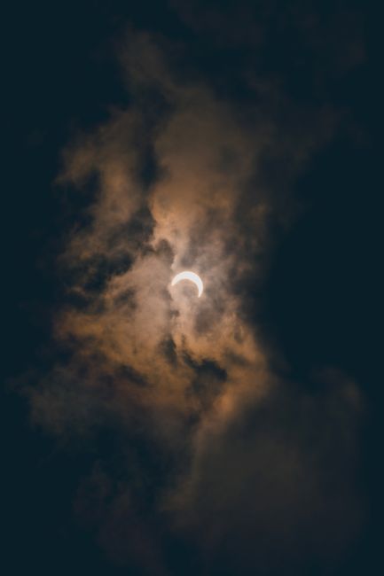 Fotomural Una vista cautivadora de un eclipse solar rodeado de nubes dramáticas y sombrías en Akumal, México.