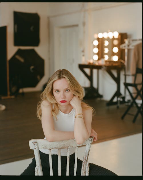 Blonde Woman Sitting Backwards on Wooden Chair