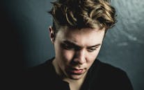 这是一张年轻人的特写肖像，背景昏暗，表情若有所思