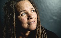 特写肖像中，一位留着辫子的女人在黑暗背景下抬头仰望，表情若有所思