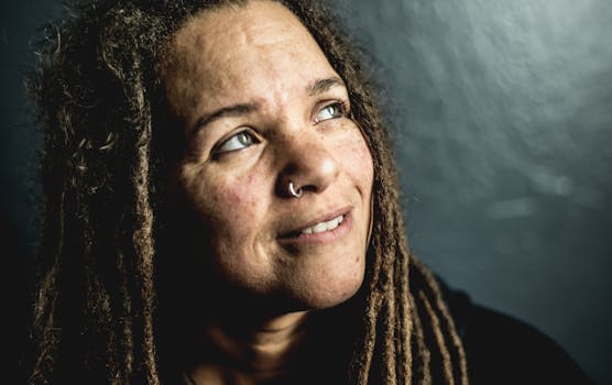 特写肖像中，一位留着辫子的女人在黑暗背景下抬头仰望，表情若有所思