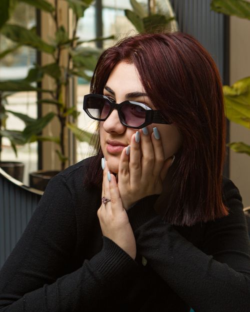 Free Portrait of a woman with dyed red hair and purple sunglasses, posing indoors. Stock Photo