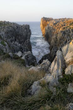 Stunning limestone cliffs of Llames de Pria, Spain framed by rugged rocks and the vibrant sunrise.