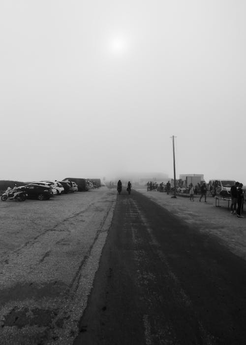 A black and white photo of people walking on a foggy road