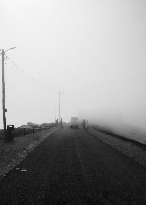 A black and white photo of a road in the fog