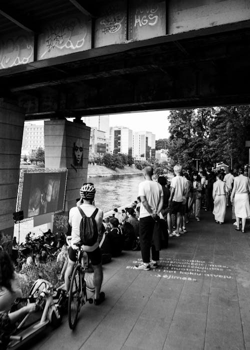 A black and white photo of people standing under a bridge