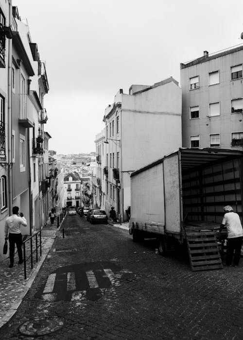 A black and white photo of a street with a truck