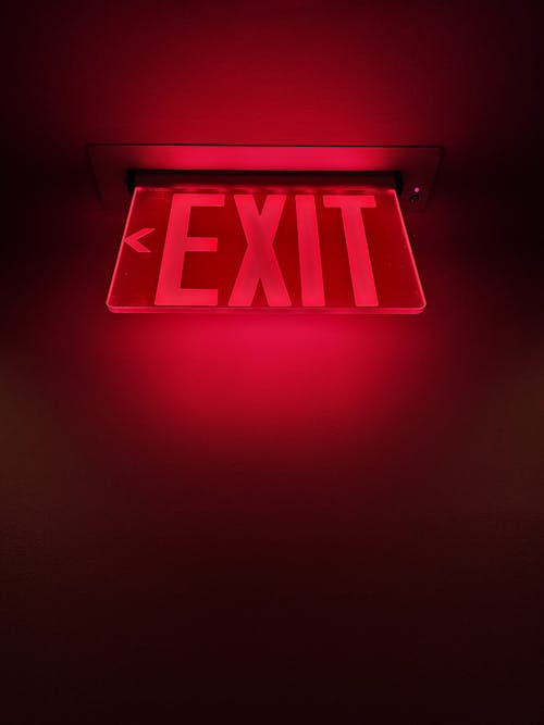 A red exit sign is illuminated in a dark room