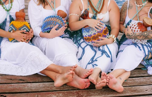 Free Four women in white dresses and sandals sitting on a dock Stock Photo