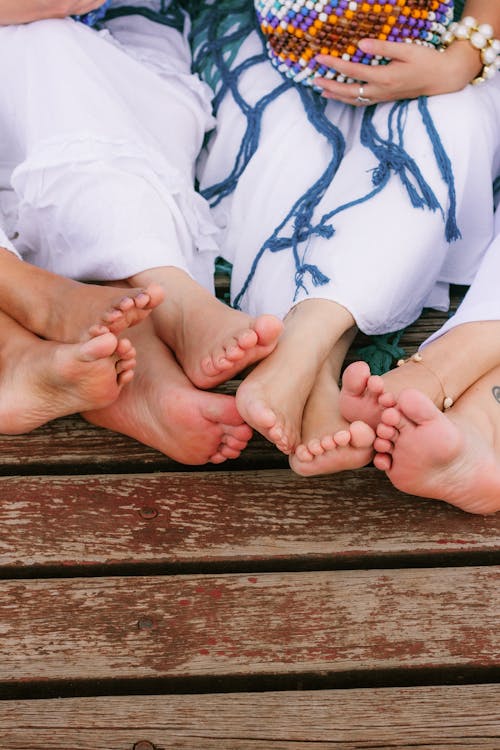 Free A group of people sitting on a wooden bench with their feet Stock Photo