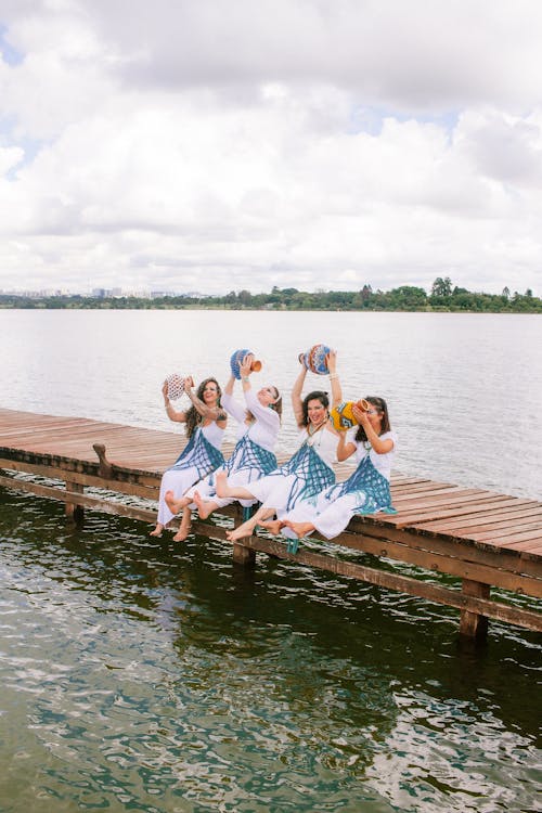 Free Four girls in blue dresses sitting on a dock Stock Photo