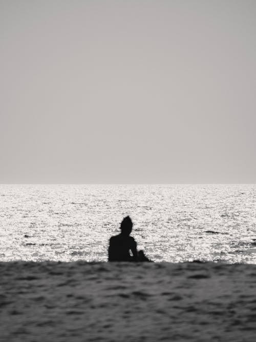 A person sitting on the beach with the ocean in the background