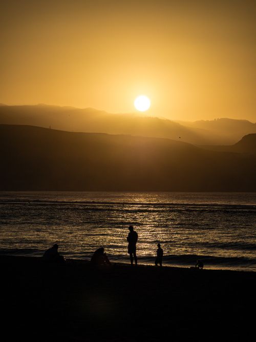 Free A serene sunset scene with silhouettes of people at Las Palmas beach, capturing warm hues and tranquil waves. Stock Photo