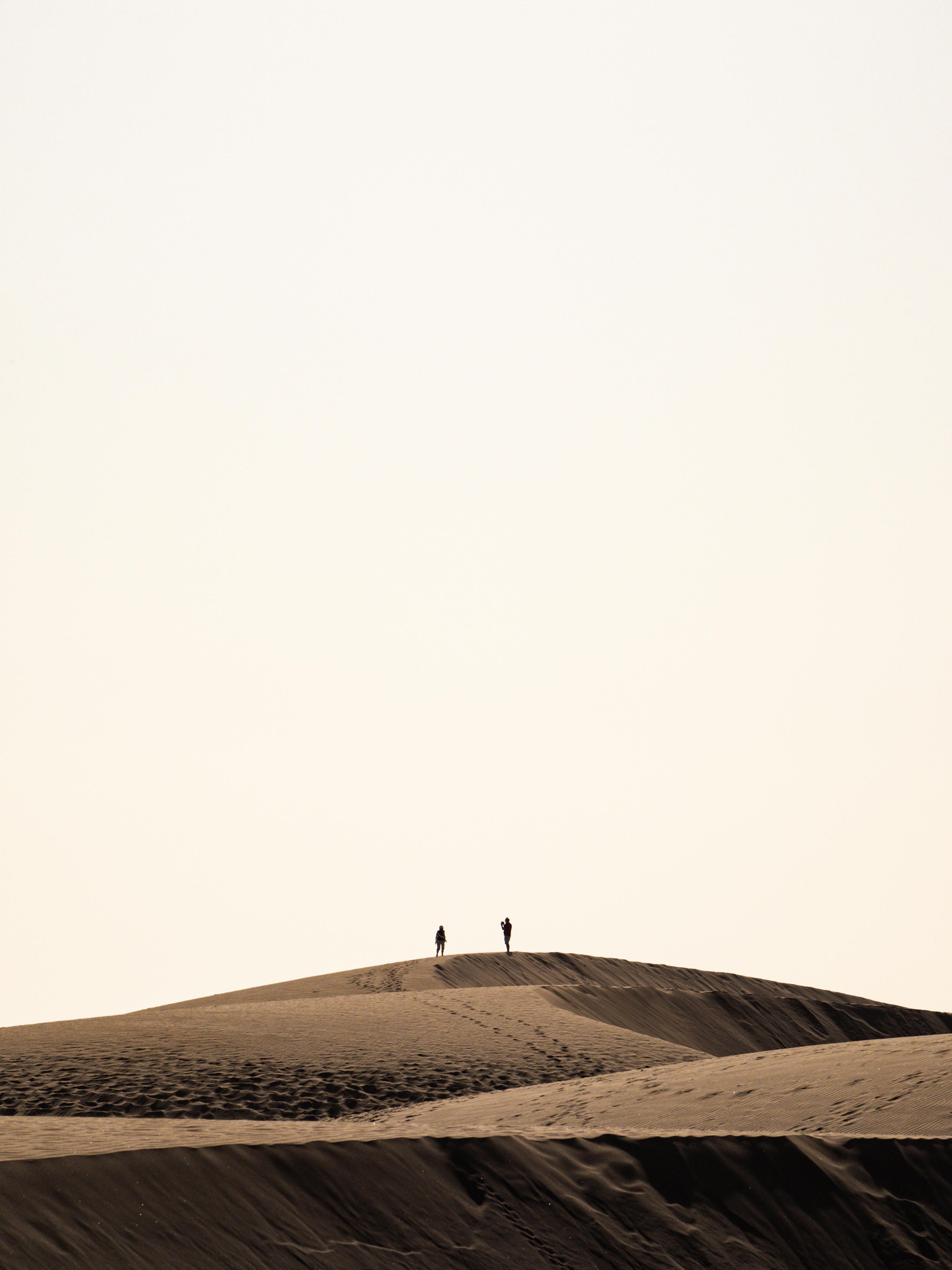 Two people silhouetted on sand dunes in Las Palmas, creating a striking minimalist view.