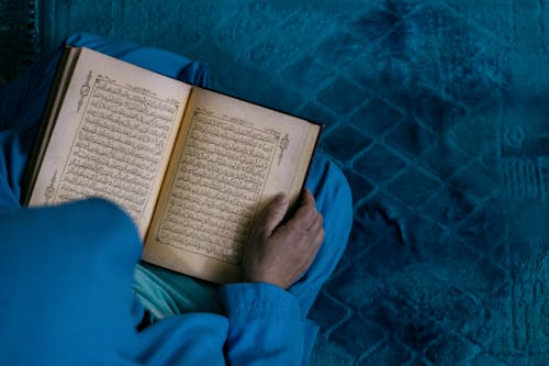 Top View of a Person Kneeling and Holding Koran 