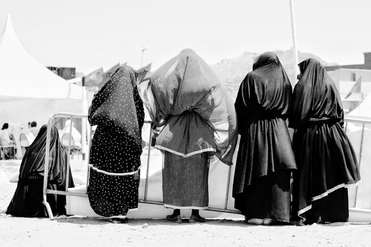 Black And White Photo Of A Group Of Women In Hijabs Walking In City 