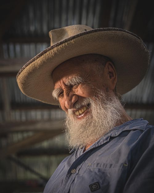 Free Elderly man with gray beard and hat smiling warmly in portrait shot. Stock Photo