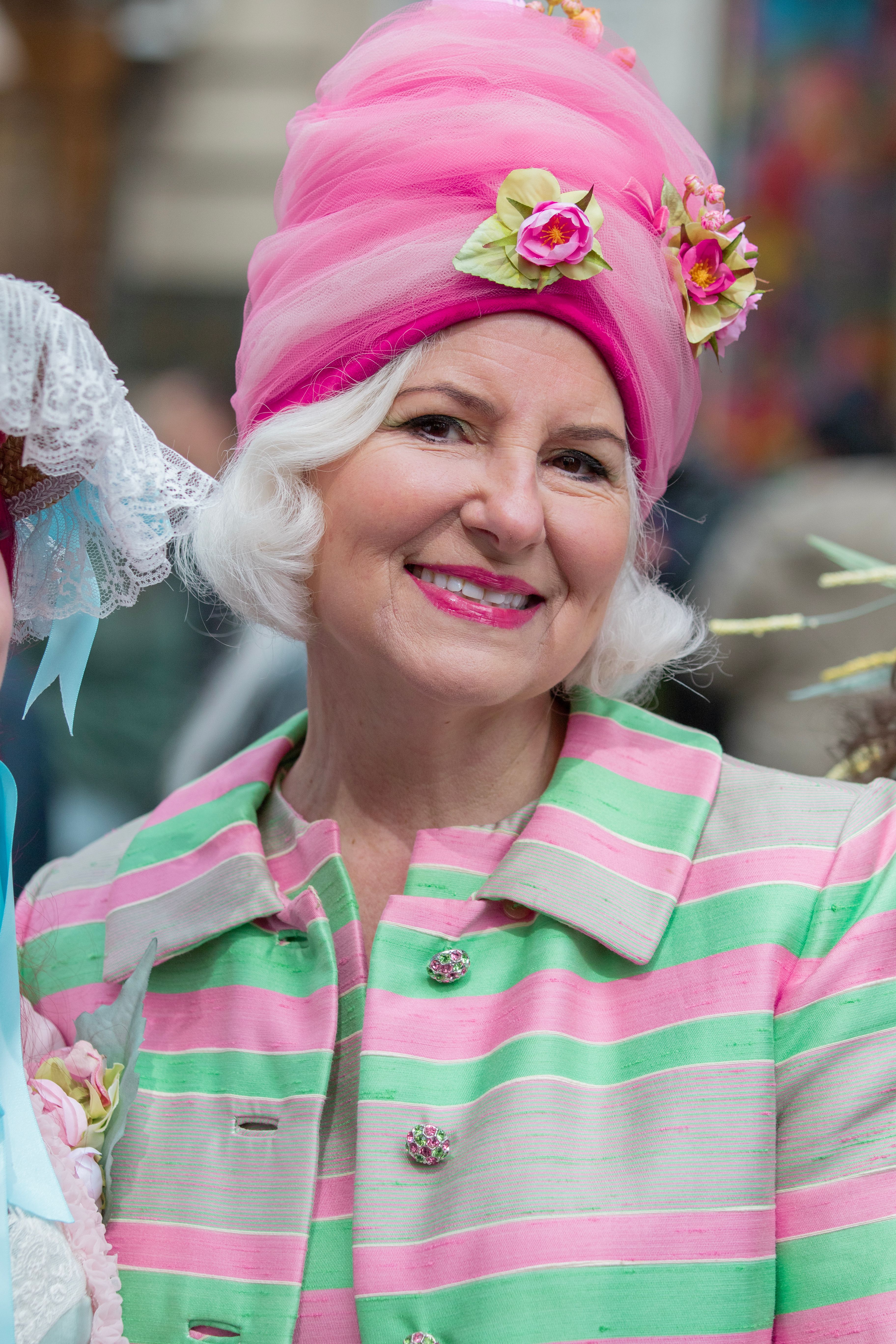 Smiling woman in festive, colorful attire at a spring parade in New York.