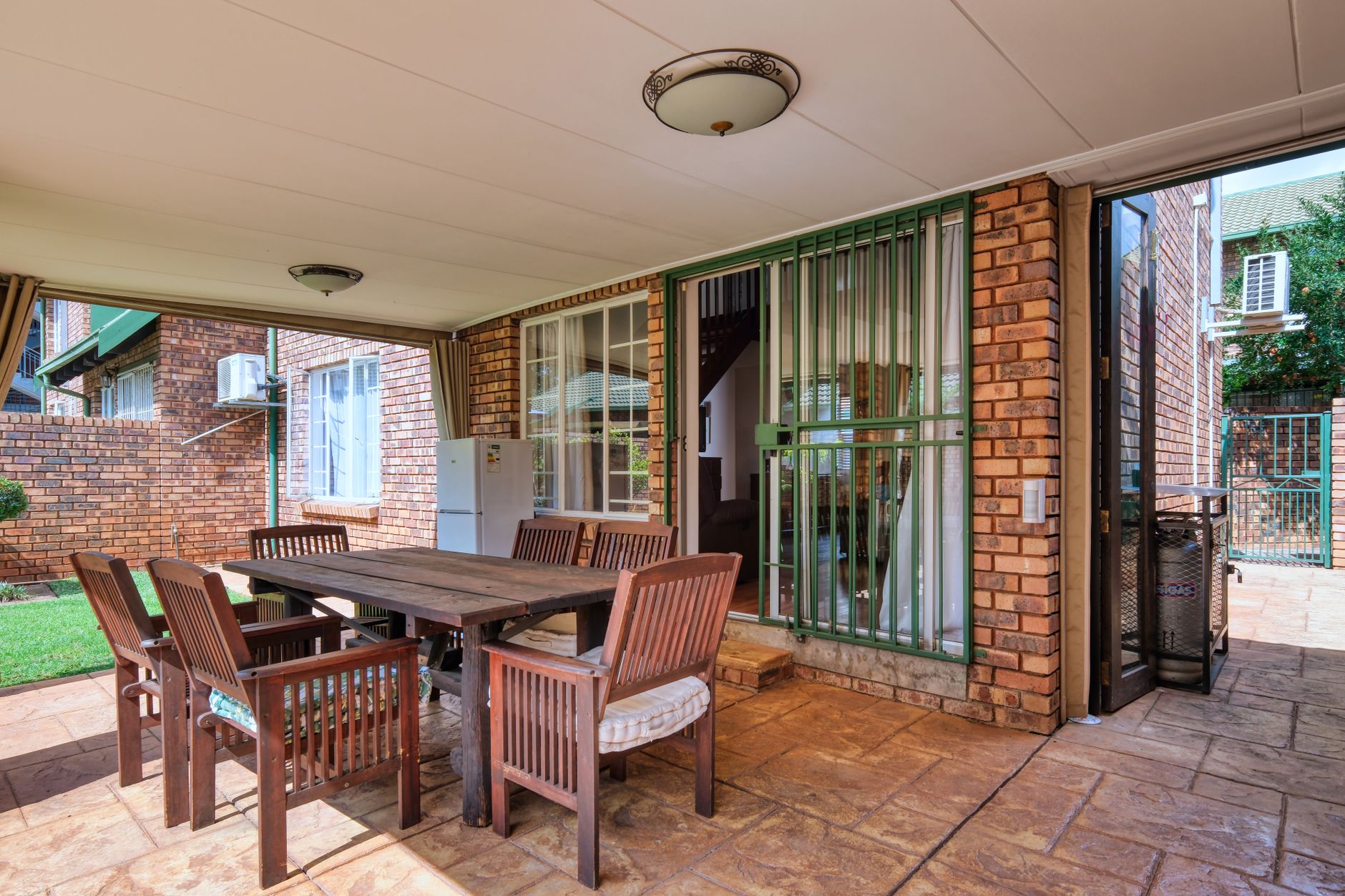 Cozy outdoor patio space with wooden furniture and brick walls in a modern home.