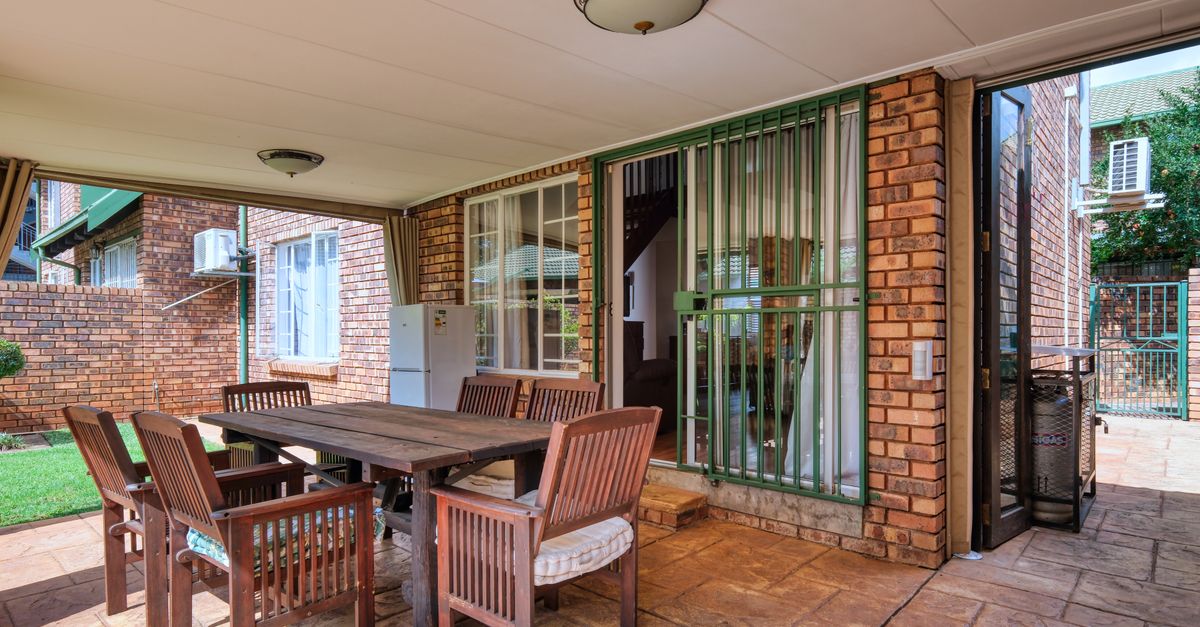 Cozy outdoor patio space with wooden furniture and brick walls in a modern home.