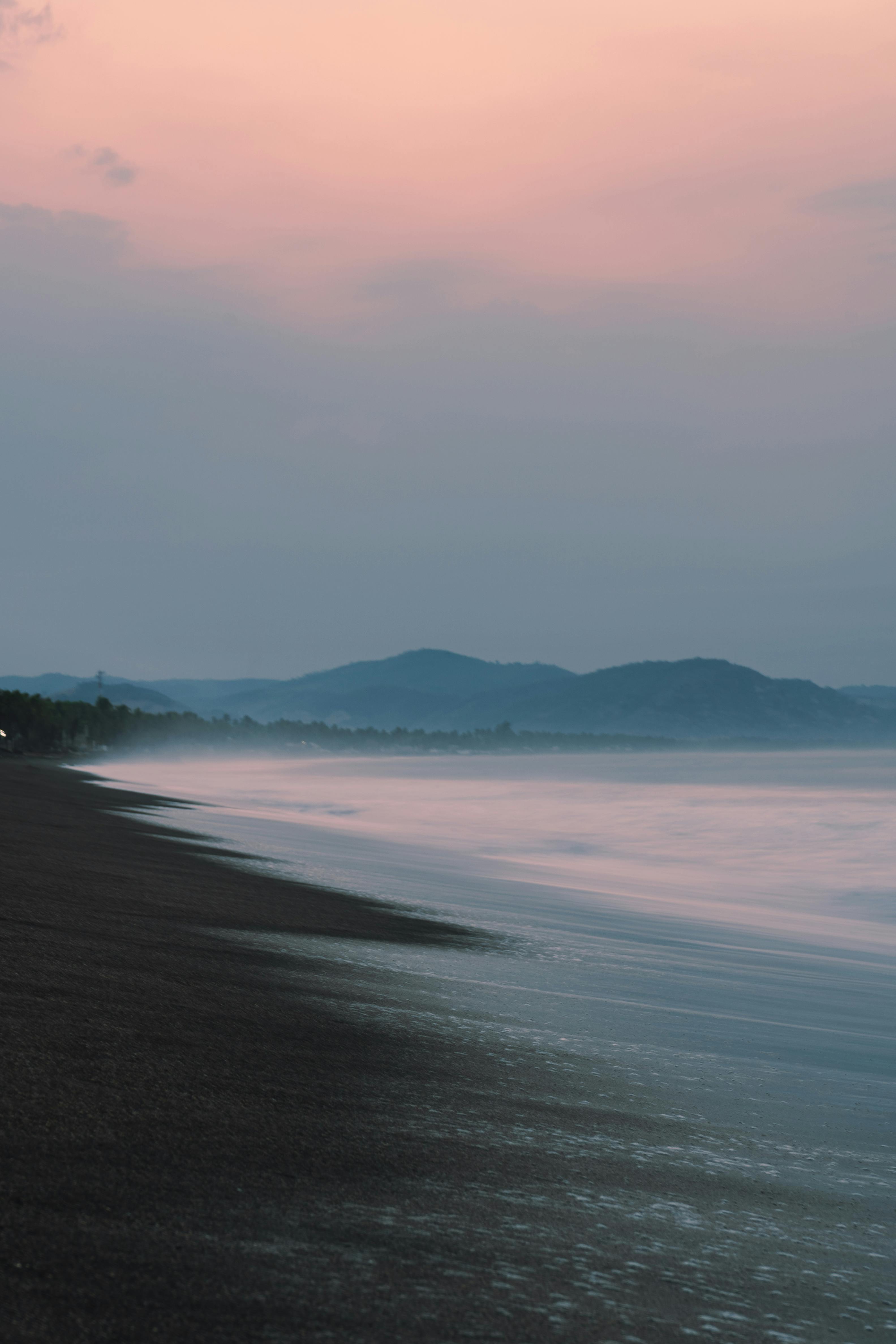 Tranquil evening scene of a beach with gentle waves and a calming sunset sky.