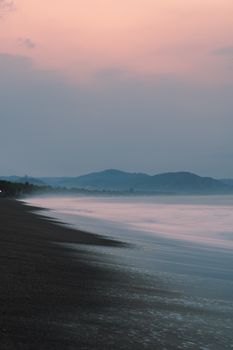 Tranquil evening scene of a beach with gentle waves and a calming sunset sky.