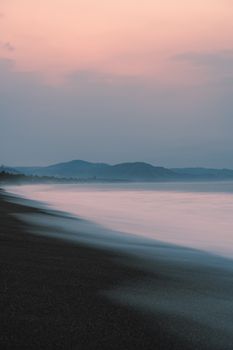 Peaceful beach scene with soft waves and pastel sunset sky.