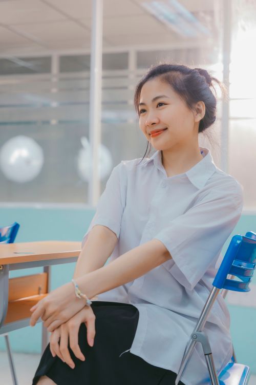 Free Portrait of a smiling woman sitting in a brightly lit office, exuding a sense of calm and confidence. Stock Photo