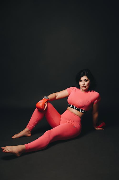 Free A woman in pink leggings and gloves sitting on the ground Stock Photo