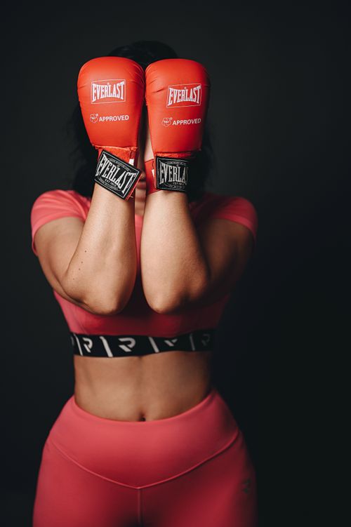 Free Strong woman athlete posing with red boxing gloves in studio setting. Stock Photo