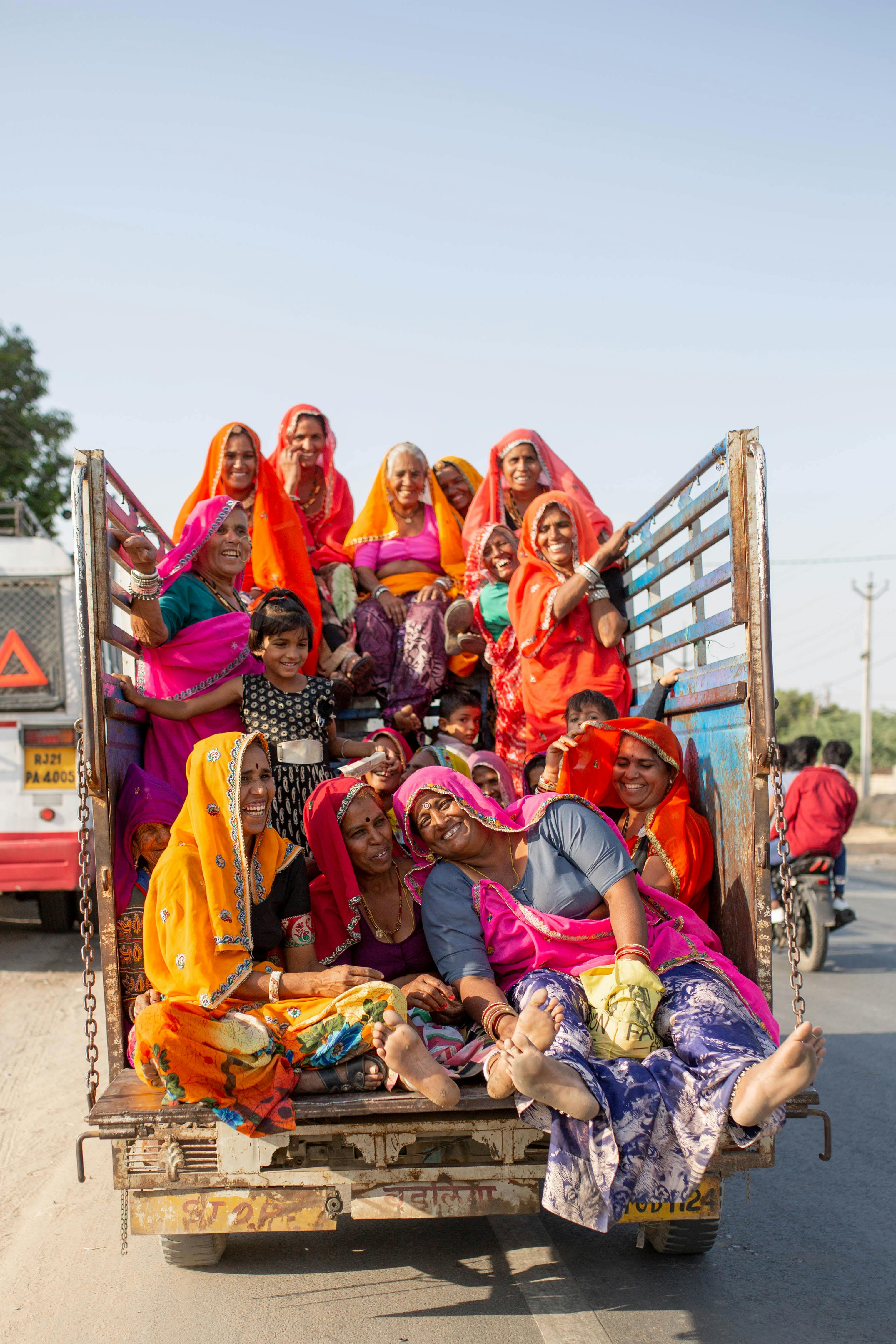 Vibrant group of smiling women and children enjoying a ride on a truck in Pushkar, India.