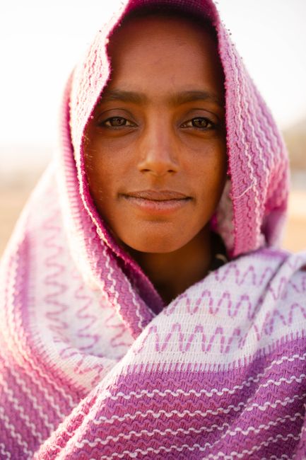 Portrait of a young woman wrapped in a colorful shawl during daytime, in Pushkar, India.