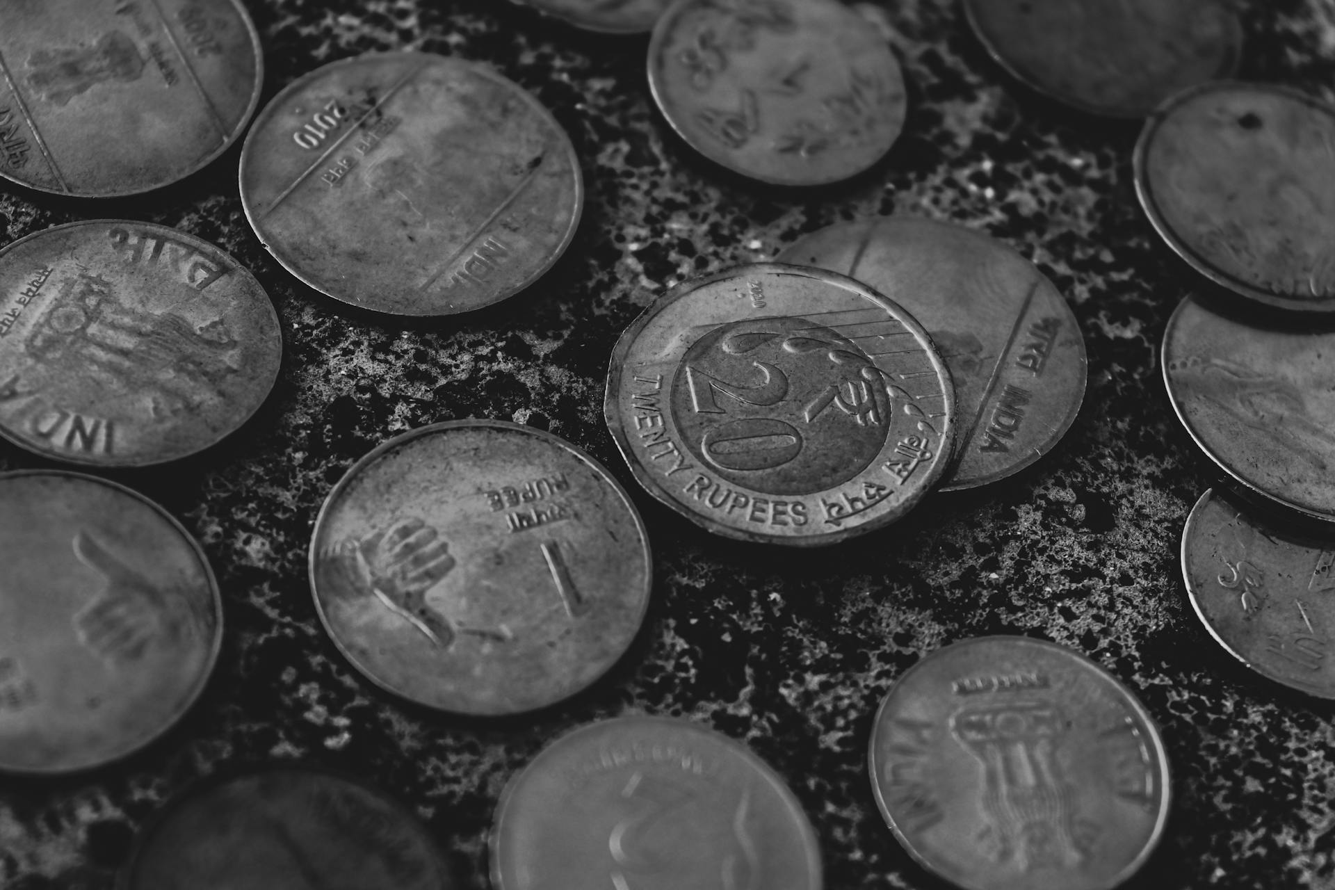 A detailed black and white macro shot of scattered Indian rupee coins, highlighting texture and design.