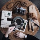 木桌上摆放着老式相机、咖啡杯、羊角面包和日记本，营造出非常适合创意早午餐的氛围