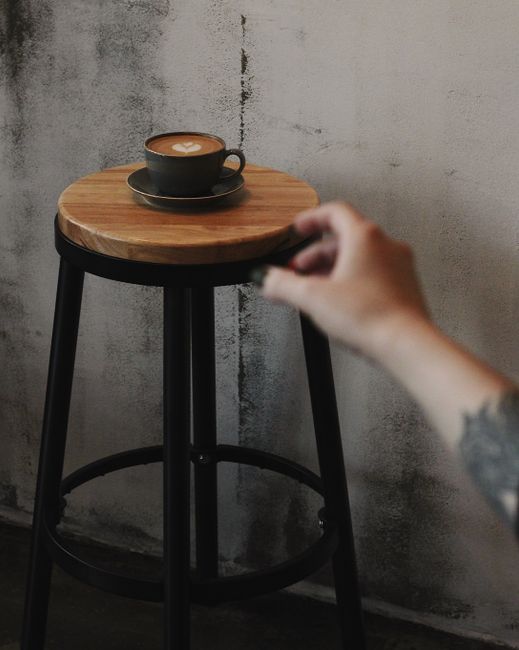 Captivating latte art displayed on a rustic wooden stool in a cozy café, ideal for a relaxing coffee break.