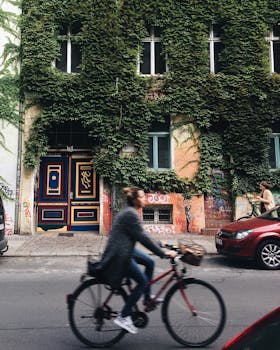 柏林市中心，一名模糊的骑车人经过一栋藤蔓覆盖的建筑，为街景增添了活力