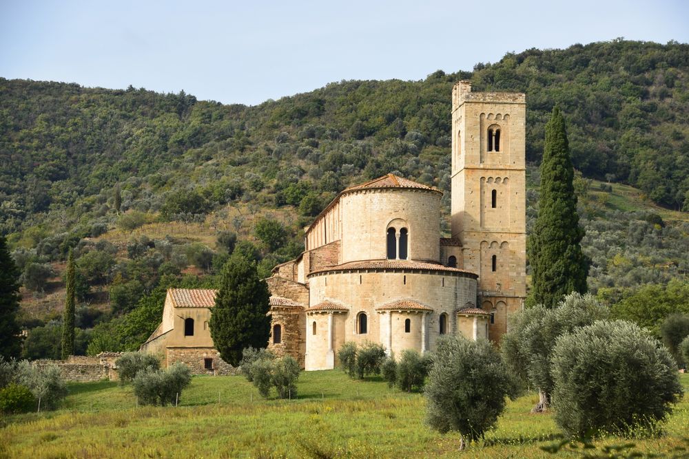 Abația Sant'Antimo din piatră, înconjurată de măslini și dealuri în Toscana