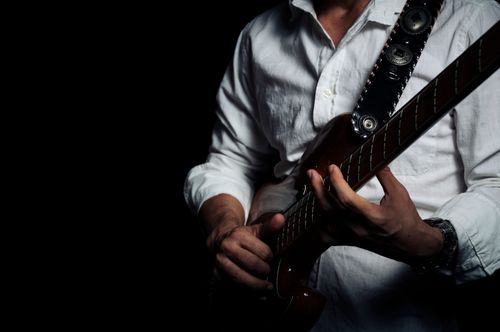 Free Musician in a white shirt playing an electric guitar in a studio setting. Stock Photo