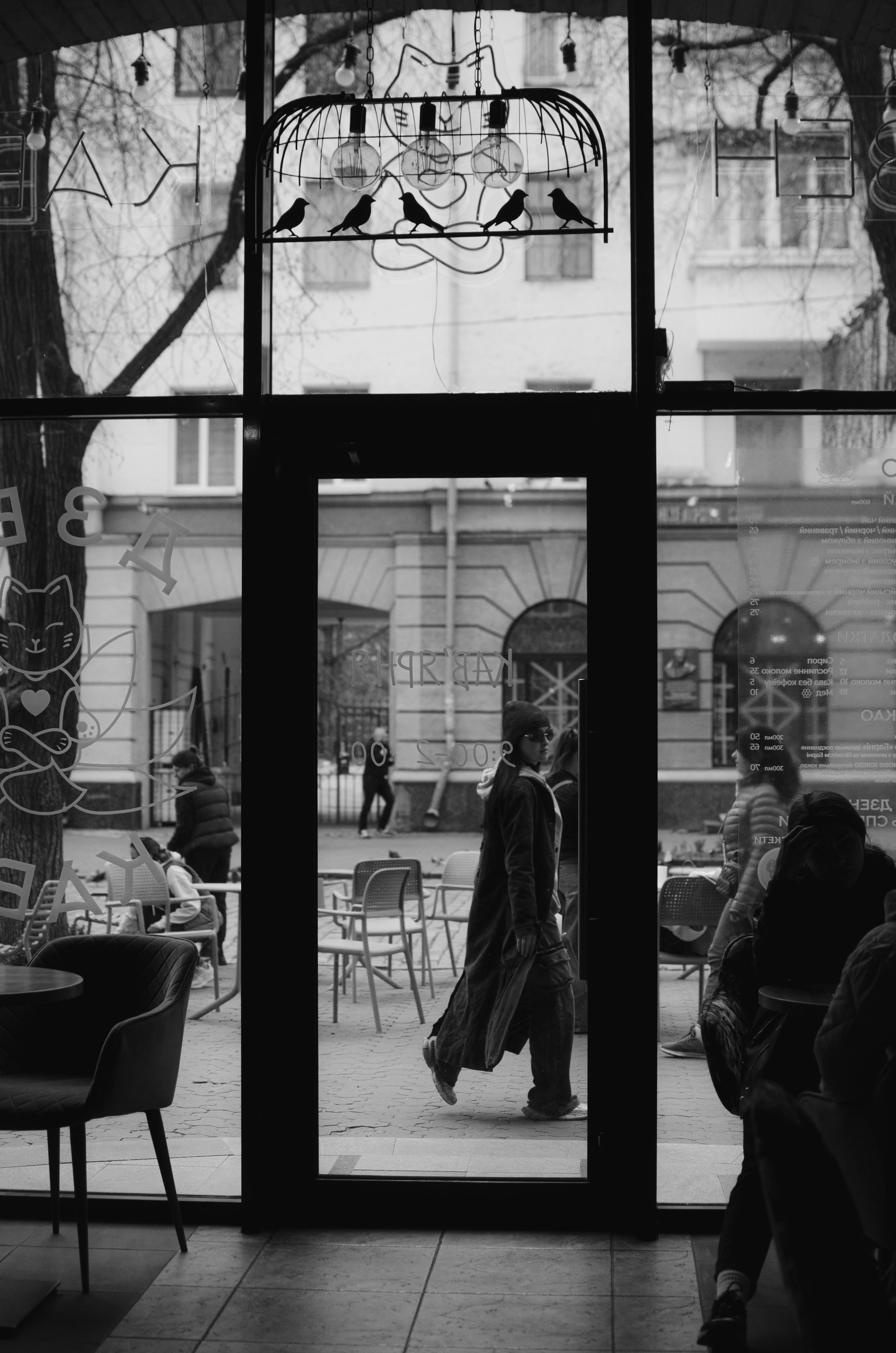 Black and white street view through a café door capturing urban life.