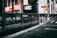 地铁入口位于城市街道旁，白天在明亮的阳光下清晰可见