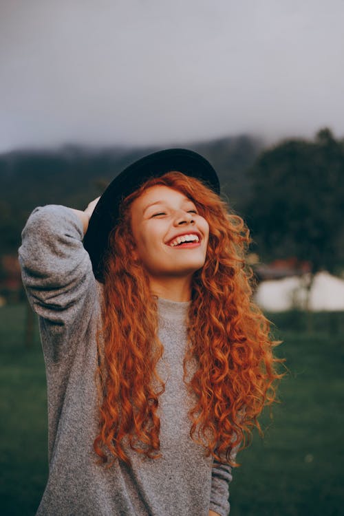 Free Woman Holding Her Hat While Smiling Stock Photo