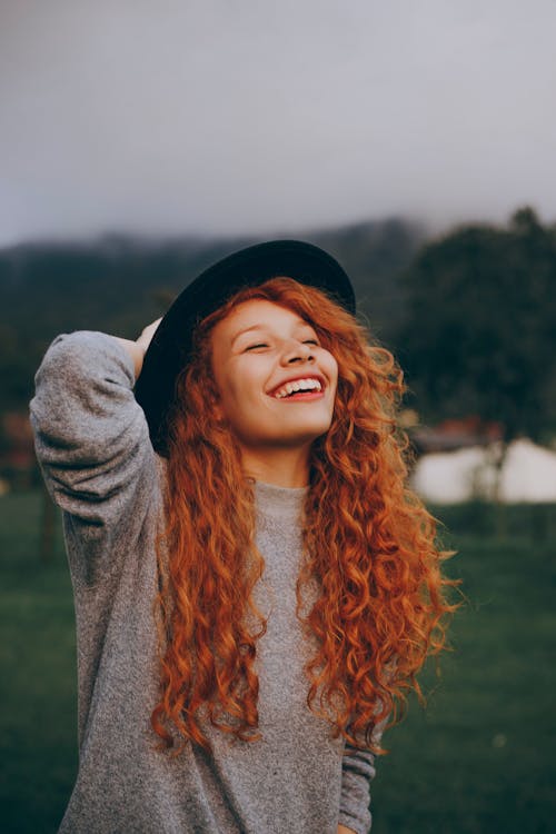 Free Woman Holding Her Hat While Smiling Stock Photo