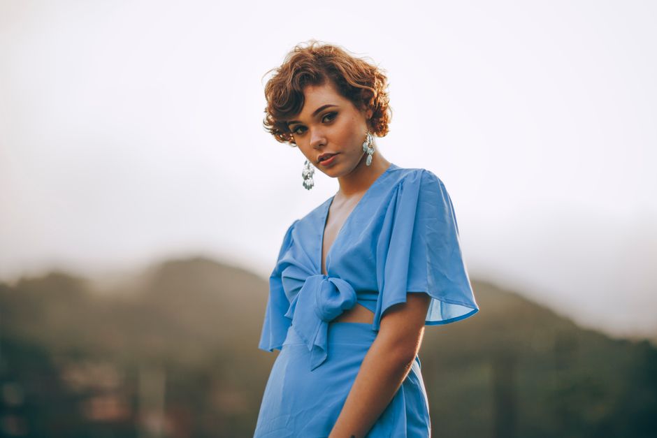 Stylish woman in a blue dress posing outdoors, showcasing elegance and modern fashion.