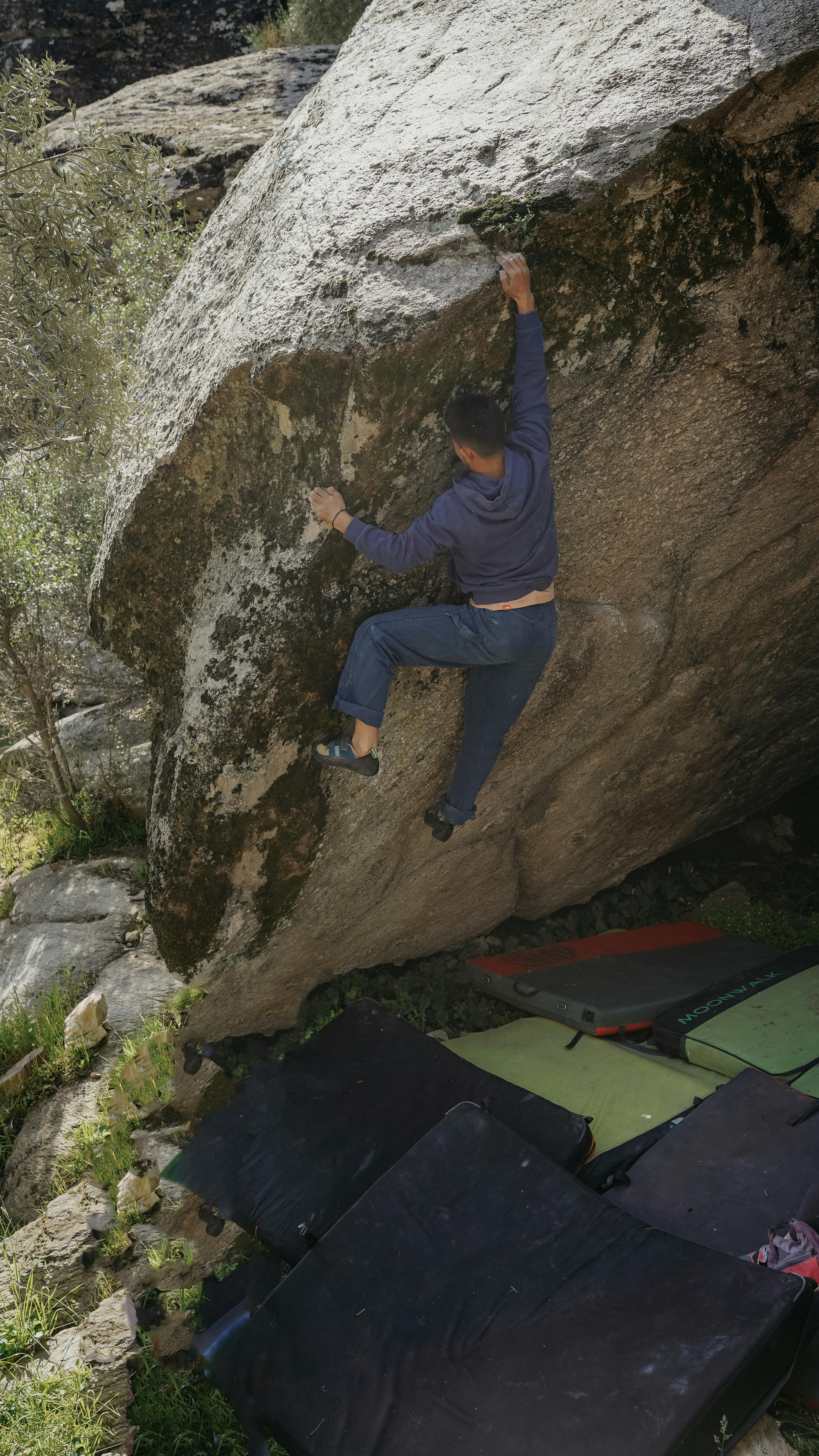 A man bouldering on a large rock formation outdoors, showcasing strength and skill.